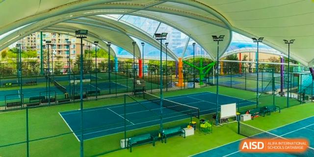A wide shot of the outdoor tennis courts at Tsinglan School, showing the fenced-in area and greenery in the background.