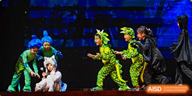 Students from Tsinglan School dressed in green costumes and performing a dance on a stage.