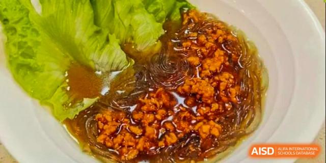 A close-up shot of a dish with meat, noodles, and lettuce, served at the cafeteria at Tsinglan School.