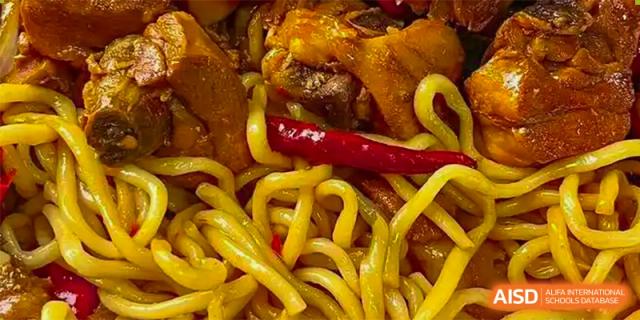 A close-up shot of cooked noodles with chili peppers, served at the cafeteria at Tsinglan School.
