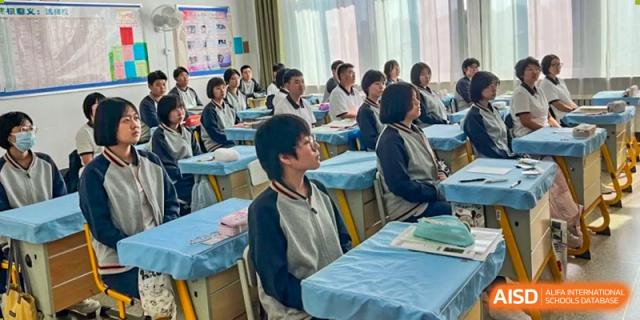 Students from Northeast Yucai Foreign Language School are paying attention to a lecture in a classroom.