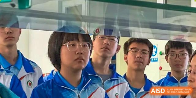 A group of male students from Northeast Yucai Foreign Language School are standing together and looking at something.