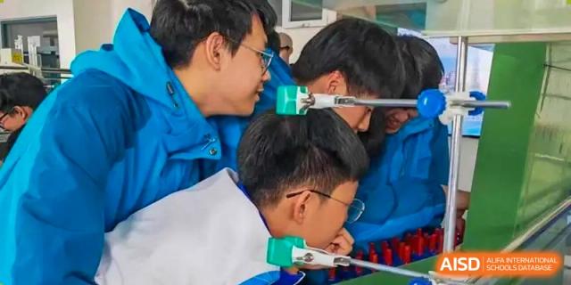 A group of students from Northeast Yucai Foreign Language School are gathered together, looking at something off-camera.