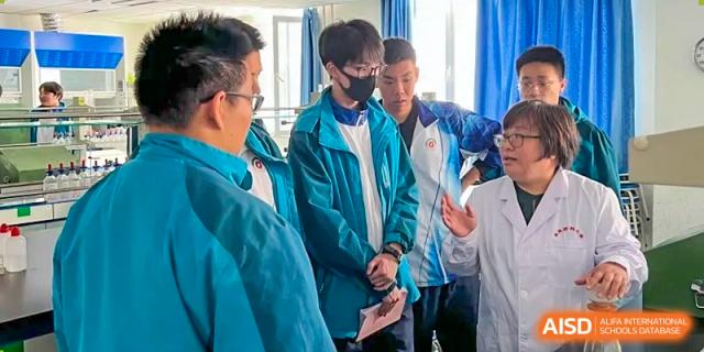 Three male students from Northeast Yucai Foreign Language School are looking at something with a teacher.