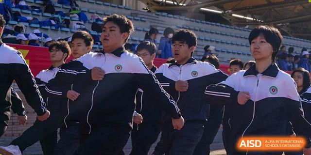 A group of students from Northeast Yucai Foreign Language School in uniform are running together.
