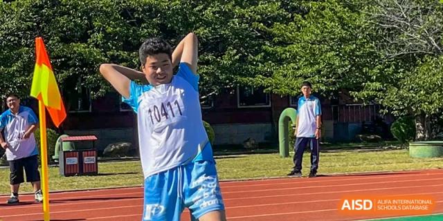 A student from Northeast Yucai Foreign Language School throws a shot put during a track and field event.