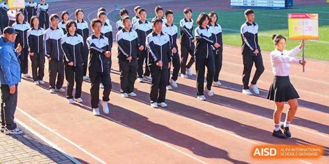 Students from Northeast Yucai Foreign Language School march in uniform on a running track.