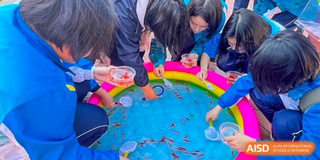 Students from Northeast Yucai Foreign Language School play a traditional goldfish scooping game.