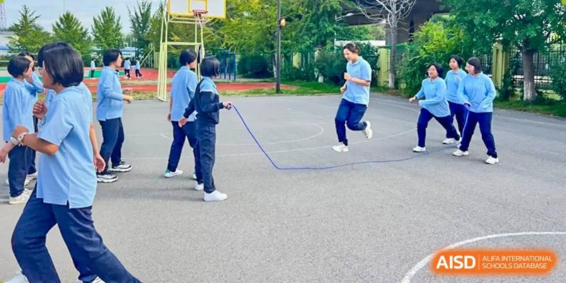 A group of students from Northeast Yucai Foreign Language School jump rope together on an outdoor court.