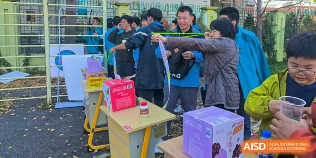 Students from Northeast Yucai Foreign Language School participate in a game where they must use chopsticks to grab items from a box.