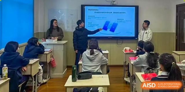 A teacher at Shanghai Foreign Language School Affiliated to SISU giving a presentation using a digital screen to a student in a classroom.