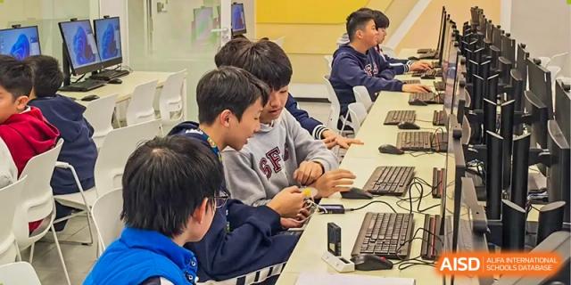 Students from Shanghai Foreign Language School Affiliated to SISU collaborating on a technical project or working on computers in a lab.