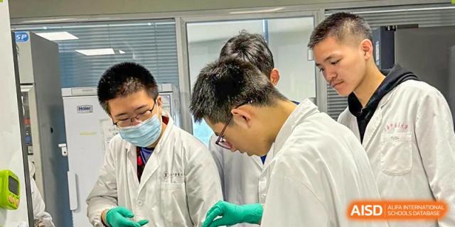 Students from Shanghai Foreign Language School Affiliated to SISU in lab coats and protective gloves working on a science experiment.
