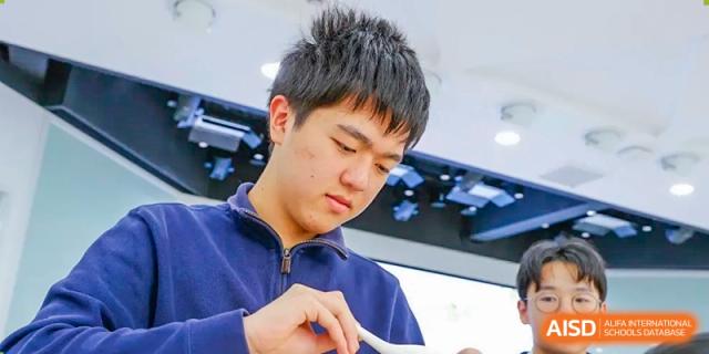 A male student from Shanghai Foreign Language School Affiliated to SISU focused on his individual work or reading material.