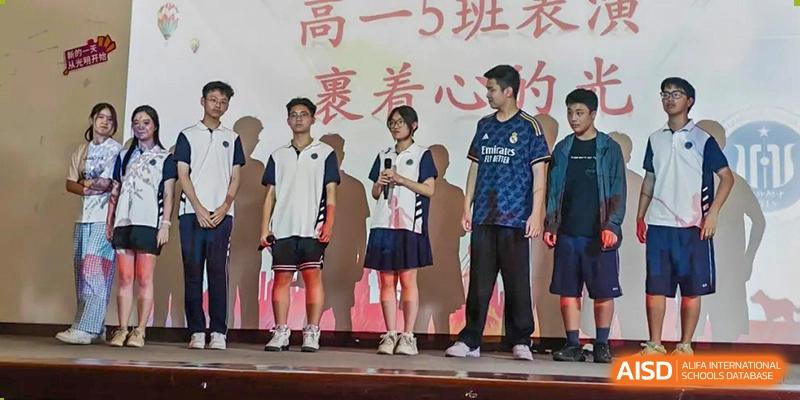 Three students from Shanghai Foreign Language School Affiliated to SISU standing on a stage, dressed in different school uniforms and casual wear.
