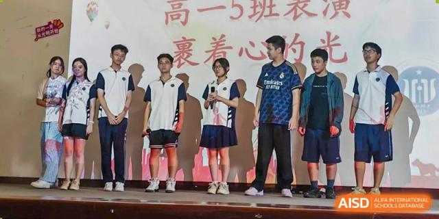 Three students from Shanghai Foreign Language School Affiliated to SISU standing on a stage, dressed in different school uniforms and casual wear.