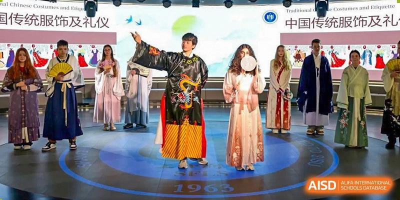 Two students from Shanghai Foreign Language School Affiliated to SISU in traditional or cultural costumes performing on a stage.