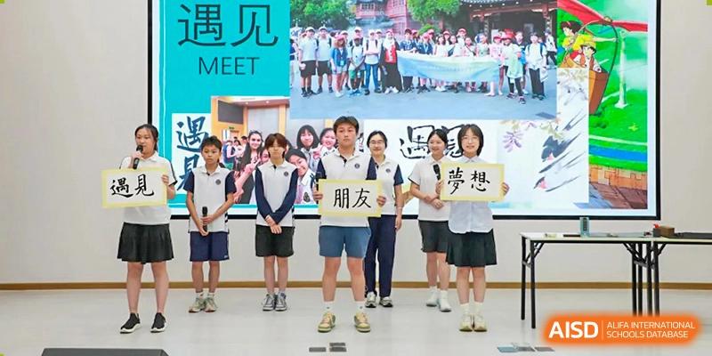 A group of students from Shanghai Foreign Language School Affiliated to SISU holding a banner with Chinese characters during an outdoor school event.