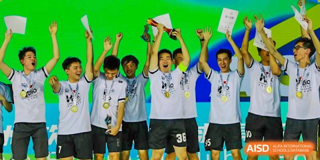 Student athletes from Shanghai Foreign Language School Affiliated to SISU in white jerseys celebrating a victory and holding a trophy with gold medals around their necks.