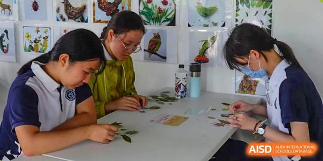 A student at Shanghai Foreign Language School Affiliated to SISU engaging in a hands-on craft or science activity with leaves and materials at a table.