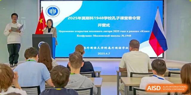 A group of students at Shanghai Foreign Language School Affiliated to SISU attending a formal opening or ceremony, with a Russian-language slide on a screen that references a Confucius School.