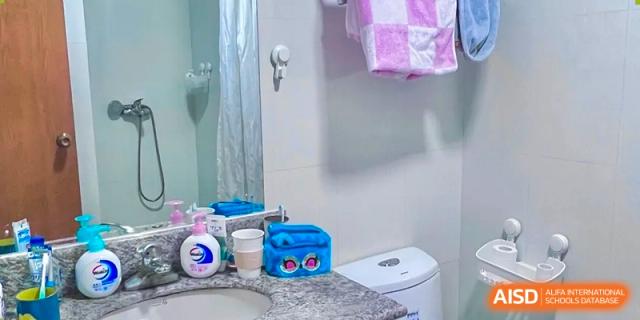 A clean bathroom setting with a toilet and toiletries on a counter in a dormitory at Shanghai Foreign Language School Affiliated to SISU.