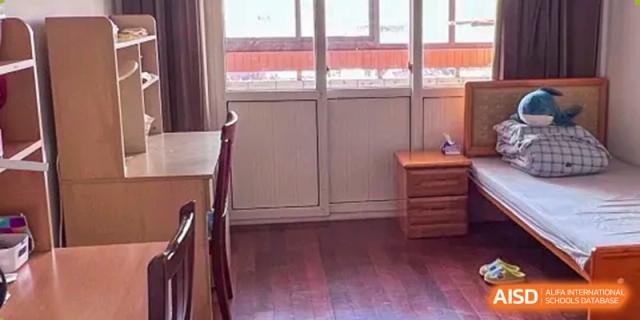 A simple dormitory room or study space with a wooden floor and natural light at Shanghai Foreign Language School Affiliated to SISU.
