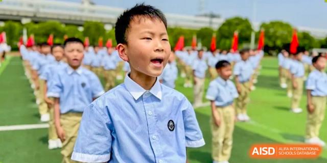 A student with his mouth open is standing outside, appearing to be singing or cheering at Shanghai Shangde Experimental School.