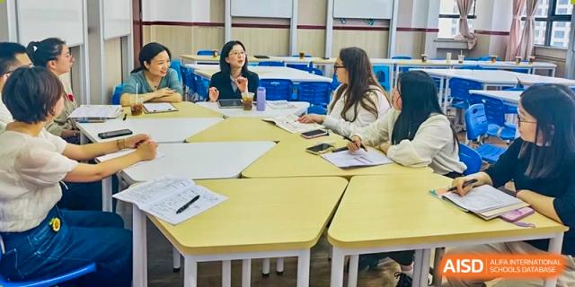 Teachers are sitting at desks in a classroom, appearing to be in a meeting or a professional development session at Shanghai Shangde Experimental School.