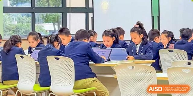 Students are sitting at desks, using tablets in a classroom at Shanghai Shangde Experimental School.
