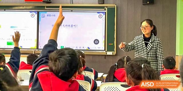Students are in a classroom with a teacher at the front, with a large smart board showing Chinese characters at Shanghai Shangde Experimental School.