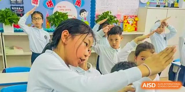 A student is raising their hand in a classroom, showing engagement and participation at Shanghai Shangde Experimental School.