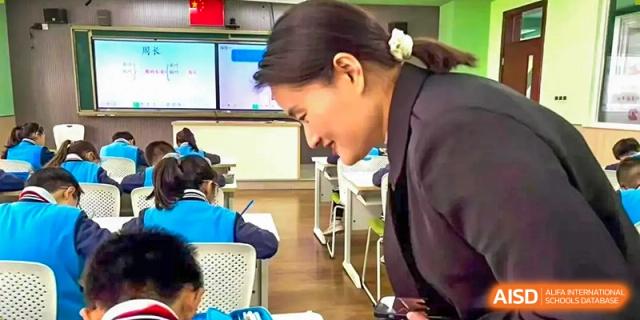 A teacher is helping a student with their schoolwork in a classroom at Shanghai Shangde Experimental School.