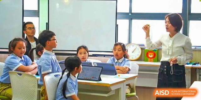 Two students are sitting at a desk and using a tablet for their lesson at Shanghai Shangde Experimental School.