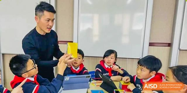 A student is holding up a yellow card in a classroom at Shanghai Shangde Experimental School.