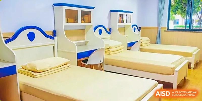 This shows a dormitory room with two beds and a desk at Shanghai Shangde Experimental School.