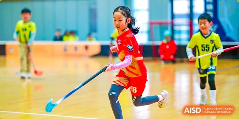 A student wearing a helmet and red jersey plays floor hockey at Shanghai Shangde Experimental School.
