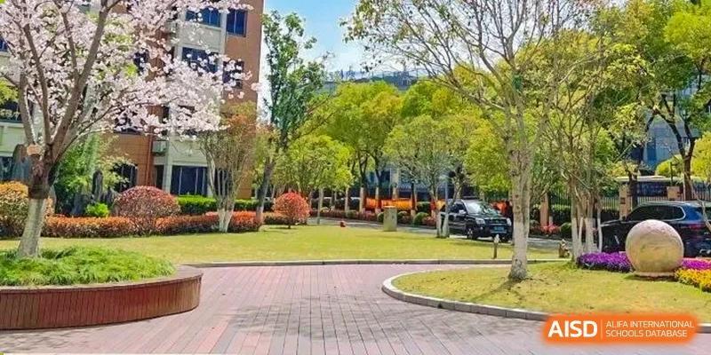 A view of the campus grounds with a paved path and green lawn at Shanghai Shangde Experimental School.