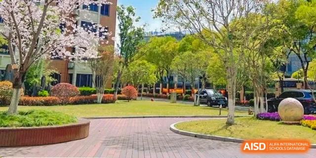 A view of the campus grounds with a paved path and green lawn at Shanghai Shangde Experimental School.