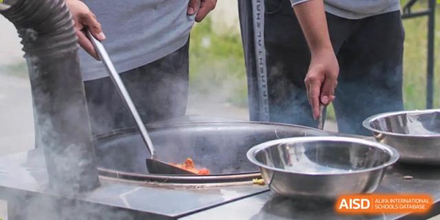 Cooking vegetables in a large wok is shown at Shanghai Shangde Experimental School.