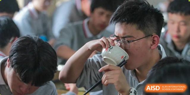 A student is eating with chopsticks from a bowl at Shanghai Shangde Experimental School.