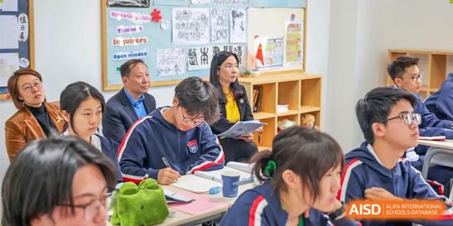 Students engaging in a classroom discussion or activity, with a teacher assisting them, at Vanke School Pudong.