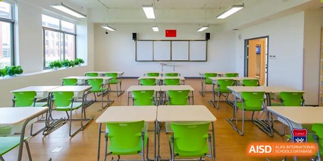 A standard academic classroom at Vanke School Pudong with bright green chairs, light-colored desks, and a whiteboard.