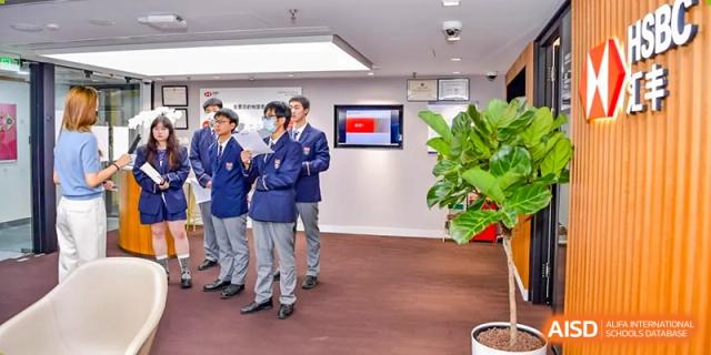 Students in uniform and an adult staff member standing in a hallway or lobby area at Vanke School Pudong.