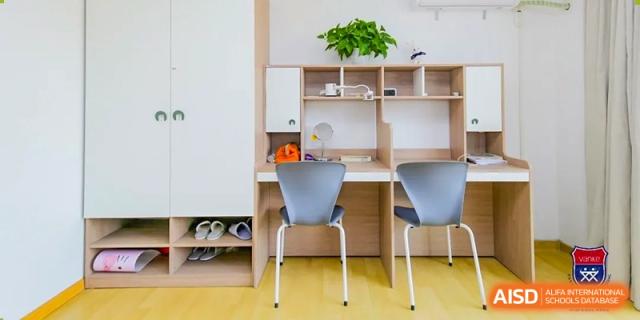 A close-up of a neat student desk and study area at Vanke School Pudong, showing shelves and an organized workspace.