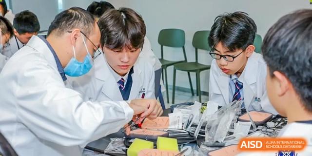 A student wearing a lab coat and working with electronics or robotics in a science or technology class at Vanke School Pudong.