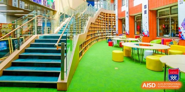 A view of the bright green carpeted, tiered seating within the library or reading nook at Vanke School Pudong.