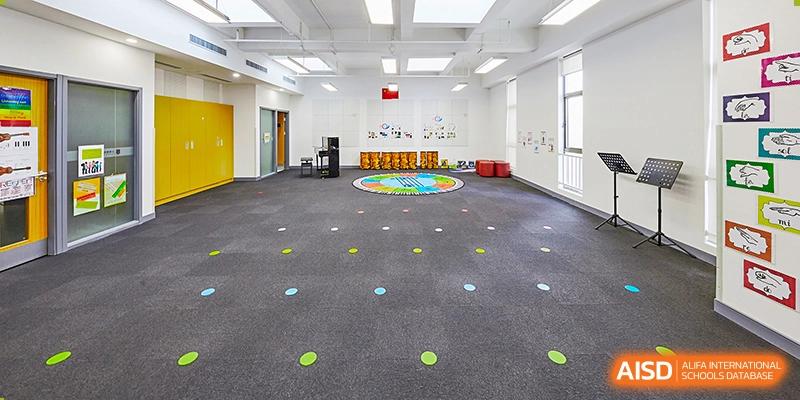 An indoor activity or play space at Vanke School Pudong, with a large carpet, colorful floor markings, and various play equipment.