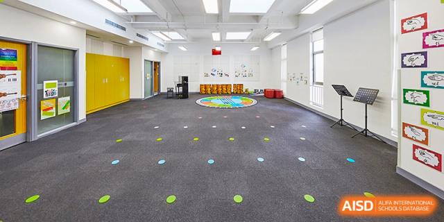 An indoor activity or play space at Vanke School Pudong, with a large carpet, colorful floor markings, and various play equipment.