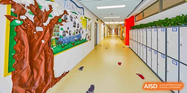 A brightly lit hallway at Vanke School Pudong with colorful wall murals and light-colored flooring, showing a perspective view down the corridor.
